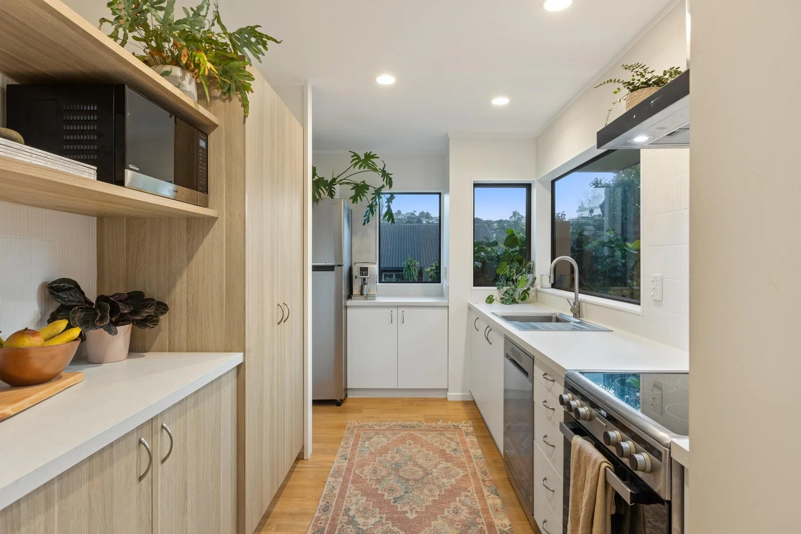 Renovated kitchen at Stanmore Bay with white cabinetry and timber flooring